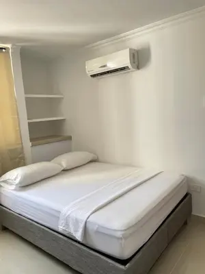 a white room with a bed and a white wall at Alojamientos Cartagena Edificio Los Delfines in Cartagena de Indias