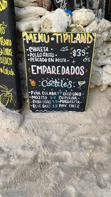 a chalkboard sign in the sand on a beach at Tipiland baru la casa del mono in Playa Blanca