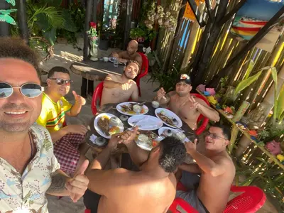 a group of men sitting around a table eating food at Tipiland baru la casa del mono in Playa Blanca