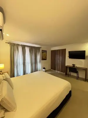 a bedroom with a large white bed and a desk at Hotel Amoek in Cartagena de Indias