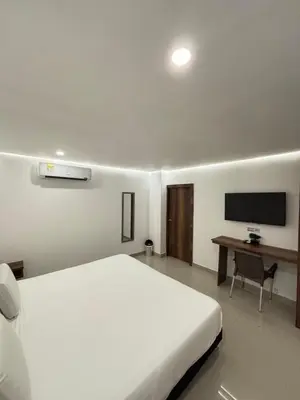 a bedroom with a bed and a desk with a television at Hotel Amoek in Cartagena de Indias
