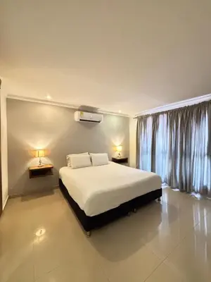 a bedroom with a bed with two lamps and a window at Hotel Amoek in Cartagena de Indias