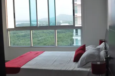 a bed in a room with a large window at Cartagena Beach Front Apartments in Cartagena de Indias