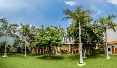 a yard with palm trees in front of a building at Hotel Genova Centro in Barranquilla