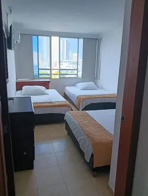 a hotel room with three beds and a window at Apartamento 1101 Edificio Nuevo Conquistador in Cartagena de Indias
