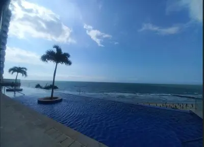 a swimming pool with a palm tree next to the beach at Mi Apartamento en Cartagena in Cartagena de Indias