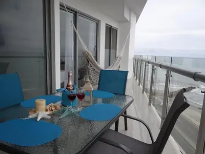 a table with chairs and wine glasses on a balcony at Mi Apartamento en Cartagena in Cartagena de Indias