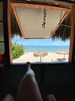 a persons leg sticking out of a window looking at the beach at Casa Akira- Rincón del Mar in San Onofre