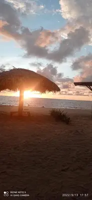 a umbrella on a beach with the sun setting at Casa Akira- Rincón del Mar in San Onofre