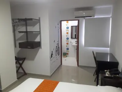 a room with a bed and a table and a bathroom at Hotel Intersuites in Barranquilla