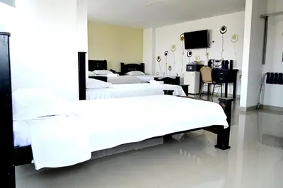 a room with four beds and a television in it at Hotel Intersuites in Barranquilla