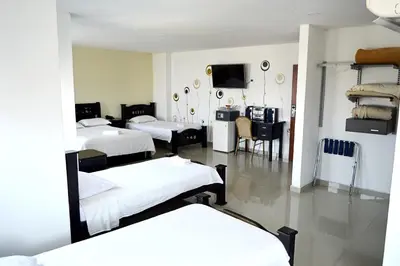 a room with three beds and a television in it at Hotel Intersuites in Barranquilla