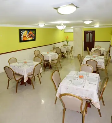 a restaurant with white tables and chairs and yellow walls at Hotel Intersuites in Barranquilla