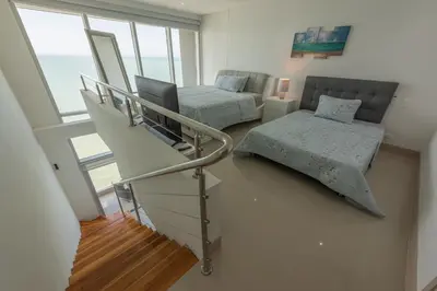 a room with a staircase and a bed and window at MURANO ELITE NEW OCEAN FRONT DUPLEx in Cartagena de Indias