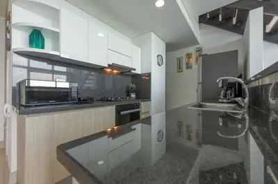 a kitchen with white cabinets and a black counter top at MURANO ELITE NEW OCEAN FRONT DUPLEx in Cartagena de Indias