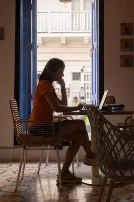 a woman sitting at a table with a laptop at Los Patios Hostel Cartagena in Cartagena de Indias