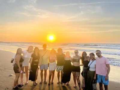 a group of people standing on the beach at sunset at Los Patios Hostel Cartagena in Cartagena de Indias