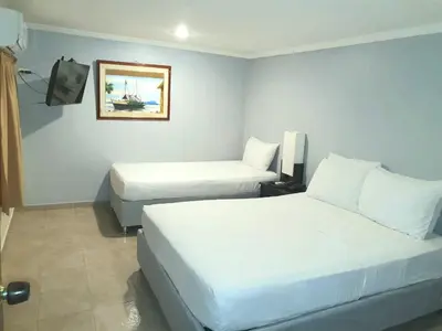 a hotel room with two beds and a tv at Hotel Puerta de Oro in Barranquilla