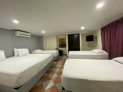 a hotel room with three beds and a tv at Hotel Puerta de Oro in Barranquilla