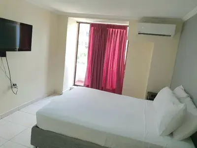 a bedroom with a large white bed and a window at Hotel Puerta de Oro in Barranquilla