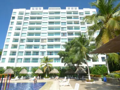 a large white building with palm trees and a swimming pool at Costa Azul Suites 905 in Santa Marta