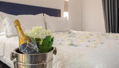 a bucket with a bottle of champagne and flowers on a bed at Hotel Santa Catalina By OxoHotel in Cartagena de Indias
