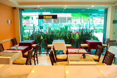a restaurant with tables and chairs and a large window at Hotel Buenos Aires in Cartagena de Indias