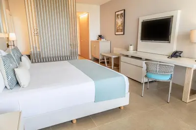 a bedroom with a bed and a desk and a television at Hotel Irotama Lago in Santa Marta