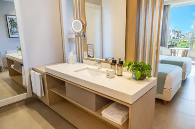 a bathroom with a sink and a mirror and a bed at Hotel Irotama Lago in Santa Marta