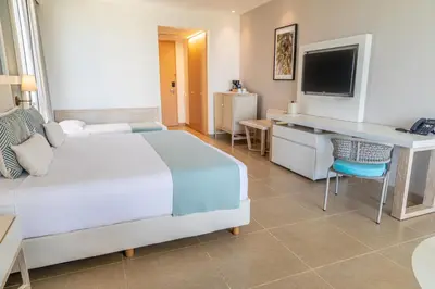 a bedroom with a bed and a desk and a television at Hotel Irotama Lago in Santa Marta