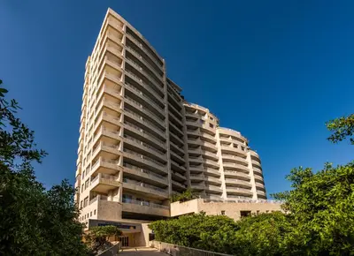 a tall apartment building with trees in front of a blue sky at Hotel Irotama del Sol in Santa Marta