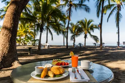 a table with two plates of food and drinks on the beach at Hotel Irotama del Sol in Santa Marta