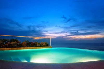 a swimming pool at night with the ocean in the background at Hotel Irotama del Sol in Santa Marta
