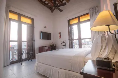 a bedroom with a bed with a lamp and windows at Hotel Monterrey in Cartagena de Indias