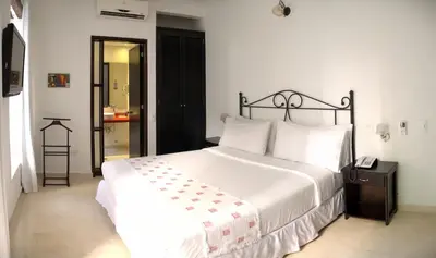 a bedroom with a large white bed and a mirror at Hotel Monterrey in Cartagena de Indias