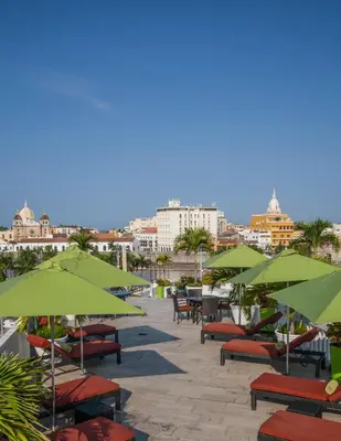 a patio with green umbrellas and tables and chairs at Hotel Monterrey in Cartagena de Indias
