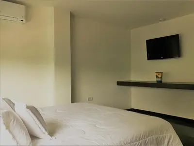 a bedroom with a white bed with a tv on the wall at Vallclaire Suites in Barranquilla