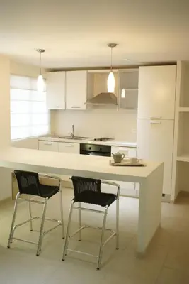 a kitchen with a white counter and two chairs at Vallclaire Suites in Barranquilla