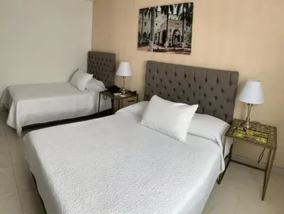 a hotel room with two beds and two lamps at Hotel Casa Nico in Barranquilla