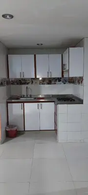 a kitchen with white cabinets and a white tile floor at Posada Dakema in Cartagena de Indias