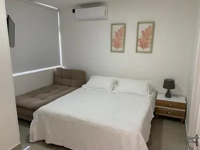 a small bedroom with a bed and a couch at Portofino Cartagena Bocagrande By ICDI in Cartagena de Indias