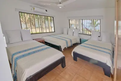 a room with three beds and two windows at Cabaña El Refugio in San Antero
