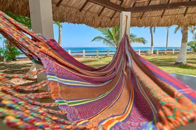 a hammock on a beach with the ocean in the background at Cabaña El Refugio in San Antero