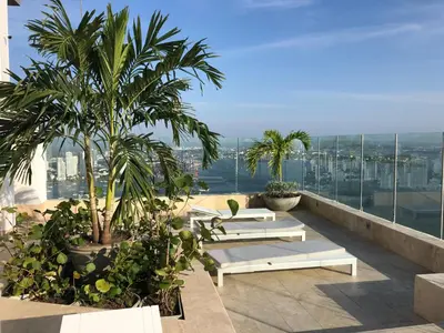 a balcony with benches and palm trees on a building at Excelente Apartamento en Murano Elite en Bocagrande, Cartagena in Cartagena de Indias