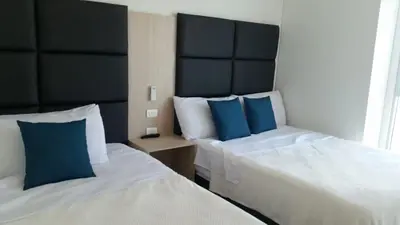 two beds in a hotel room with blue pillows at Excelente Apartamento en Murano Elite en Bocagrande, Cartagena in Cartagena de Indias