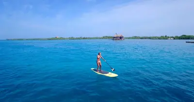 a woman on a paddle board in the water at Hotel Punta Faro in Isla Mucura