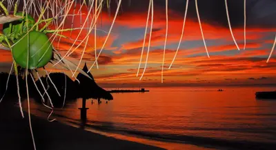 a sunset on a beach with a body of water at Hotel Punta Faro in Isla Mucura