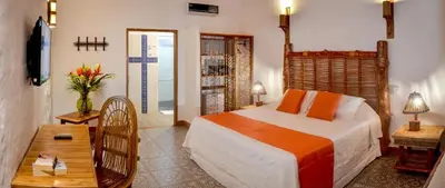 a bedroom with a bed and a table and a television at Hotel Punta Faro in Isla Mucura