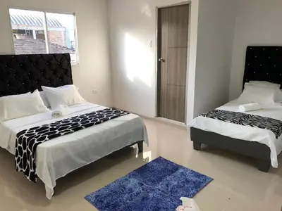 a bedroom with two beds and a blue rug at Hotel Platinum Barranquilla in Barranquilla