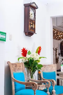 a clock on the wall next to two chairs with flowers at Balcones de Venecia in Cartagena de Indias